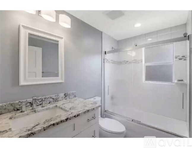 A bathroom with a marble countertop and a walk-in shower.