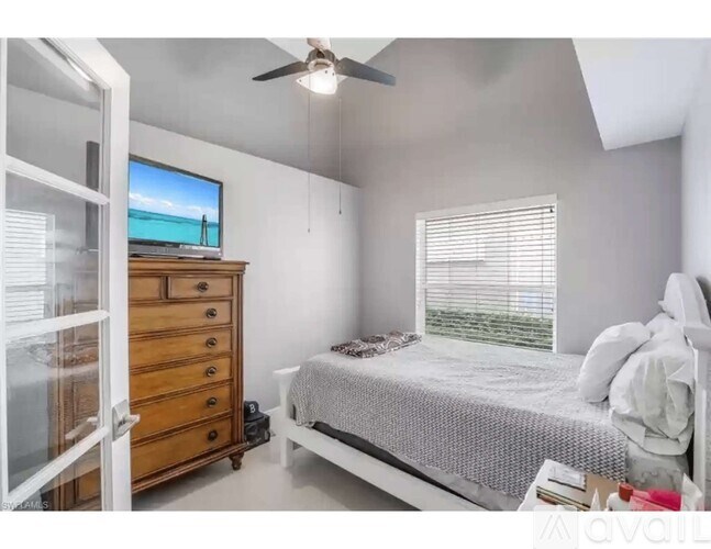 A bedroom with a bed, dresser, and a television on top of the dresser.