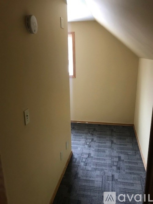 A hallway with a carpeted floor and a door on the left.