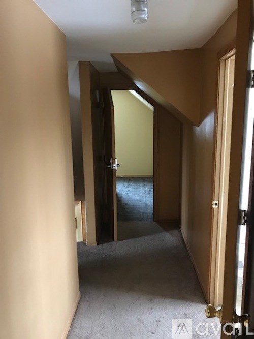 A hallway with a carpeted floor and wooden doors.
