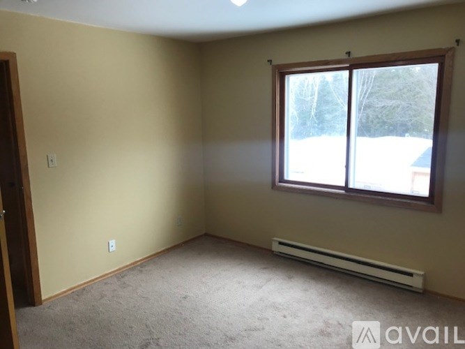 A room with a window and a carpeted floor.