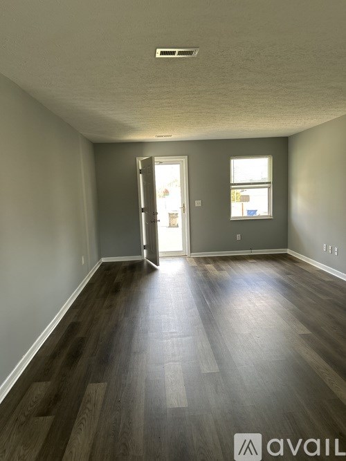 A room with a wooden floor and a door leading to a hallway.