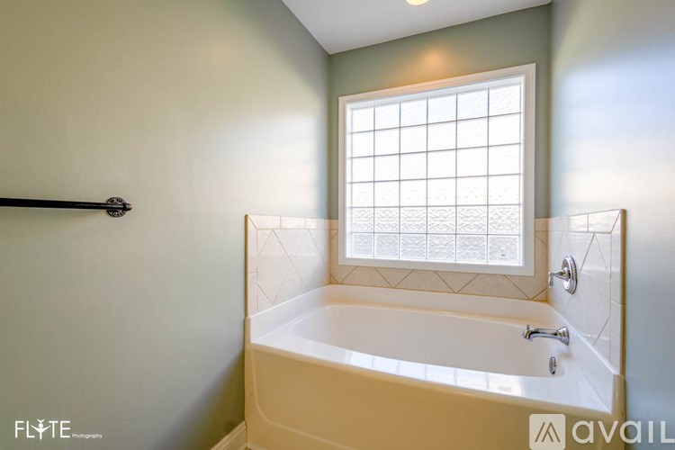 A bathroom with a tub, window, and a shower.