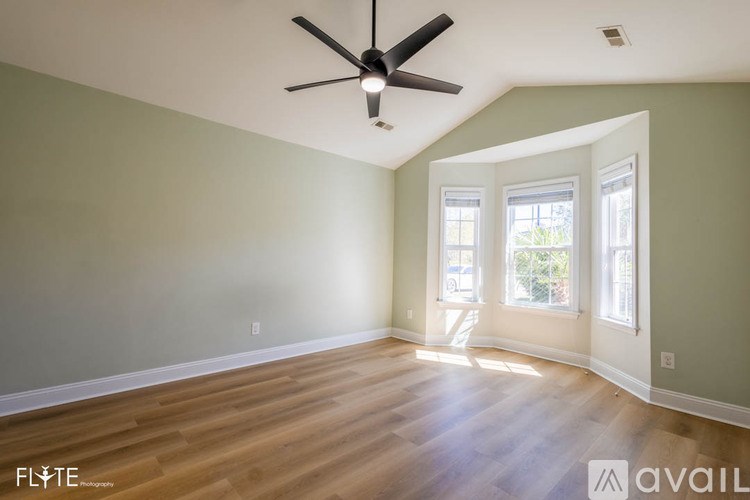 A room with a ceiling fan and wooden flooring.