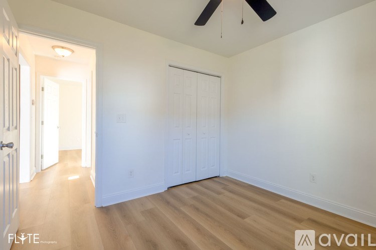 A room with a ceiling fan and wooden flooring.