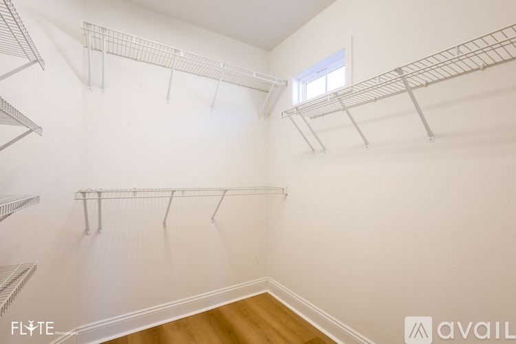 Empty walk-in closet with white walls and wooden floor.