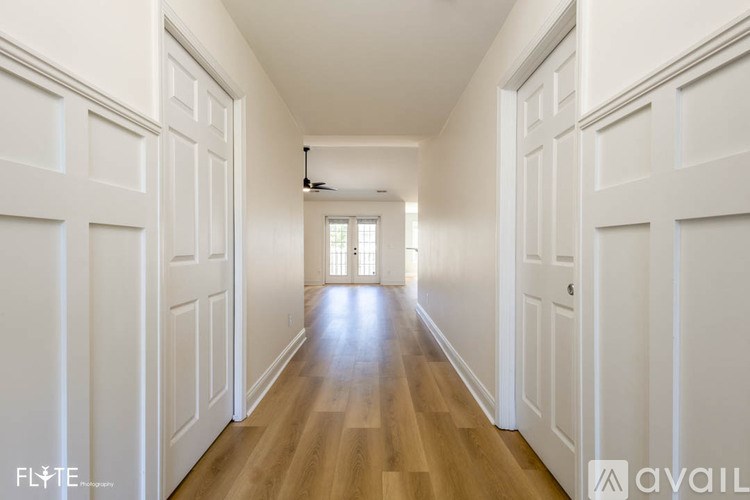 A long hallway with white doors on both sides and a light at the end.