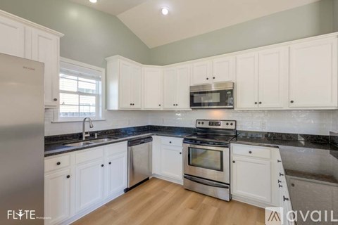 A kitchen with white cabinets and a black countertop.