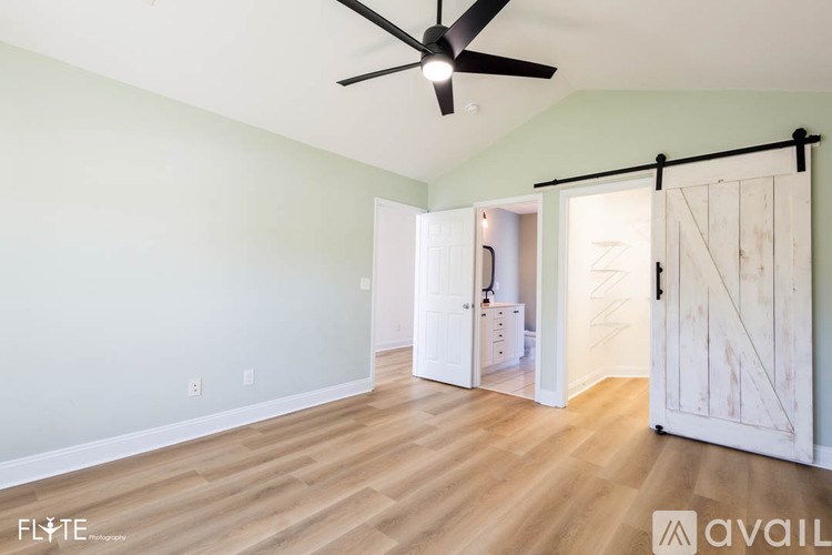 A room with a ceiling fan and a sliding barn door.