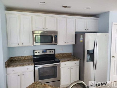 A kitchen with white cabinets and a granite countertop.