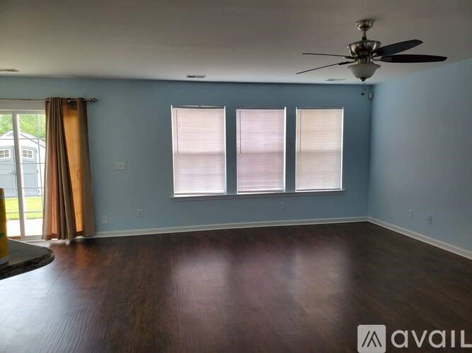 A room with a ceiling fan and three windows.