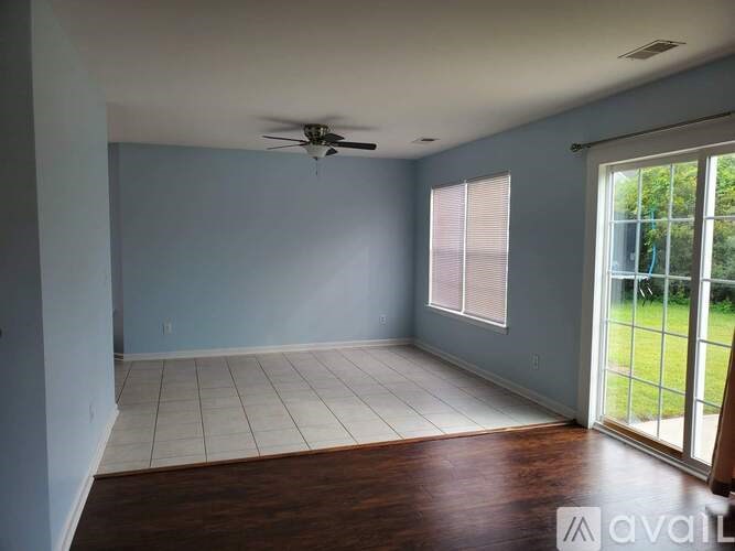A room with a ceiling fan and sliding glass doors.
