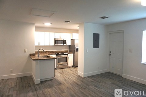 A kitchen with white cabinets and a wooden floor.
