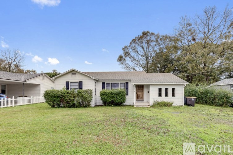 A white house with a brown roof and a green lawn in front.