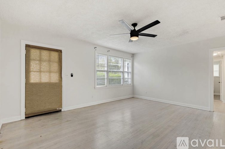 A room with a ceiling fan and a window with blinds.