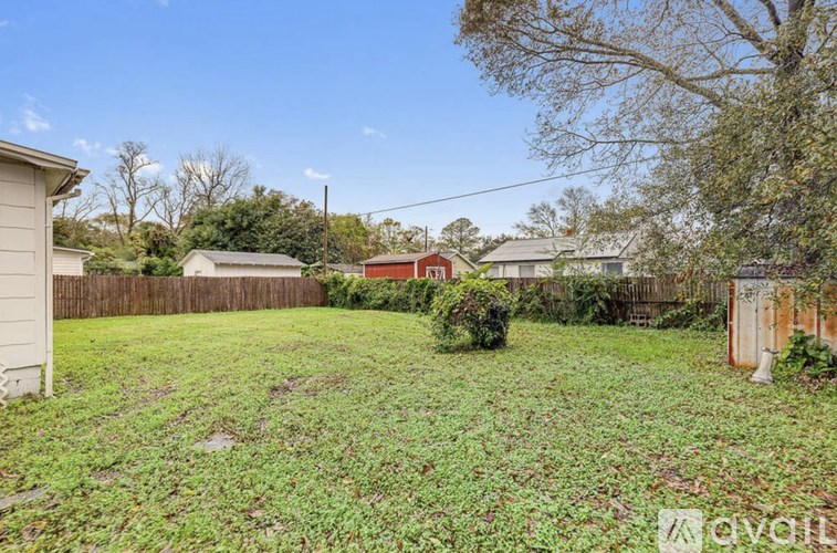A backyard with a fence and a small tree.
