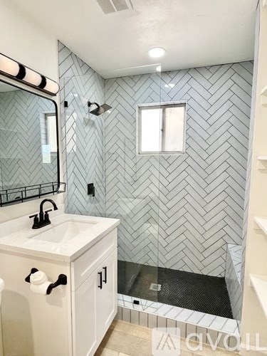 A bathroom with a white sink and a shower with a glass door.