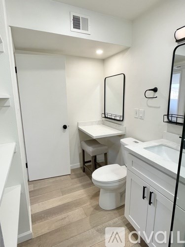 A white bathroom with a toilet, sink, and mirror.