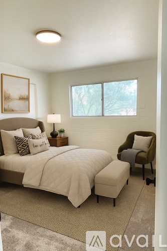 A bedroom with a bed, chair, and window.