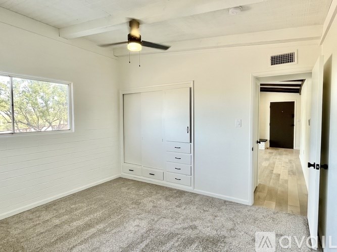 A room with a whiteboard, a ceiling fan, and a window with a view of trees.
