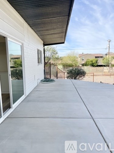 A patio area of a house with a white wall and a black roof.