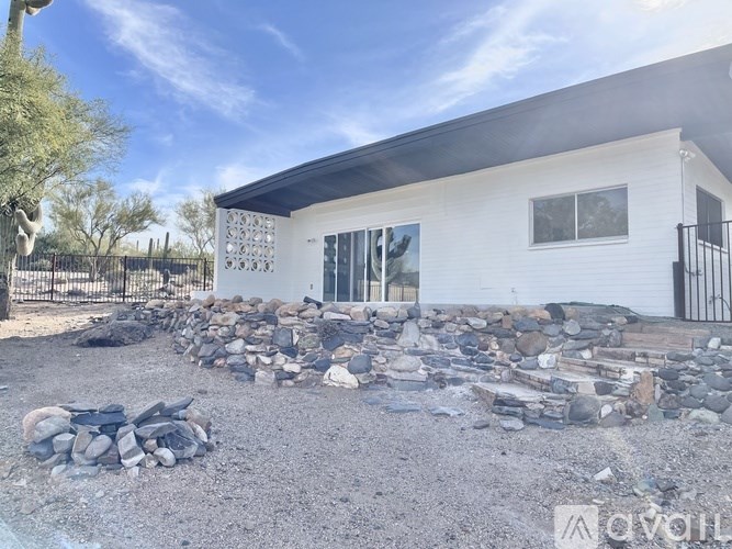 A modern house with a white exterior and a stone wall in front.