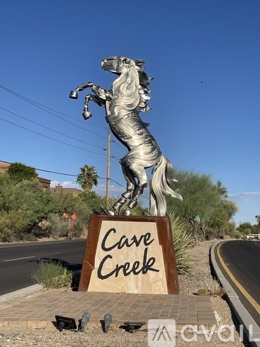 A statue of a horse holding a ribbon with the words "Cave Creek" written on it.