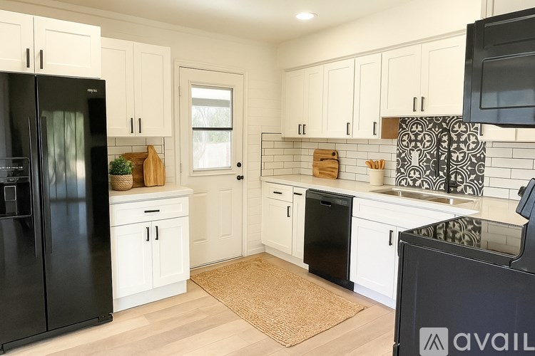 A kitchen with black appliances and white cabinets.