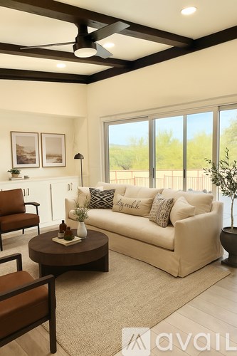 A living room with a white couch, a brown armchair, a coffee table, and a ceiling fan.