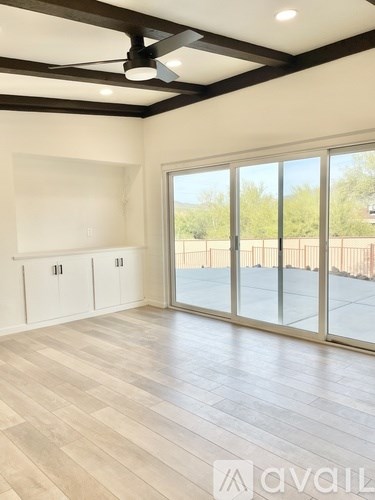 A room with a ceiling fan and sliding glass doors.