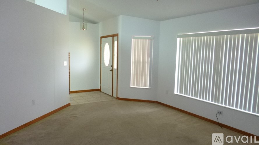 A room with a door, a window with blinds, and a wall with a light switch.