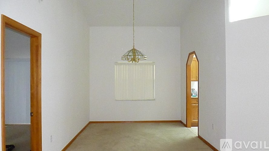 A room with a hanging light fixture and a door on the left.