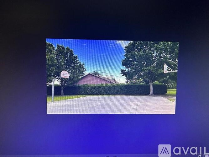 A screen displays an image of a house with a driveway and trees.