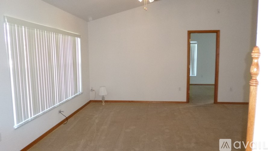 A room with a wooden floor and a large window with blinds.