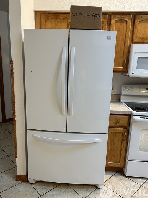 A white fridge with a card on top saying July 18, 2023.