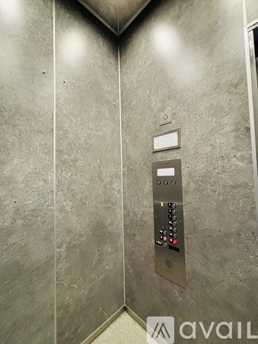 A silver elevator control panel with buttons and a display.