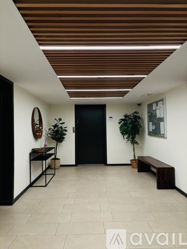A hallway with a bench, a table, and a plant.