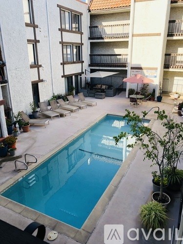 A pool surrounded by patio furniture and potted plants.