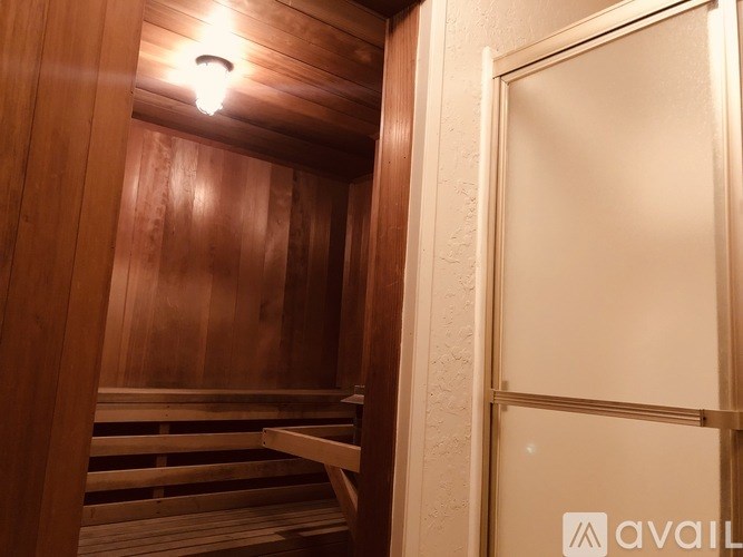A wooden sauna with a door open to a bathroom.