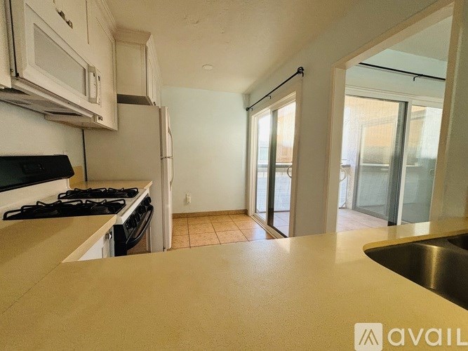 A kitchen with a stove, sink, and cabinets.