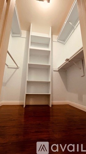 A white shelving unit in a room with wooden floors.