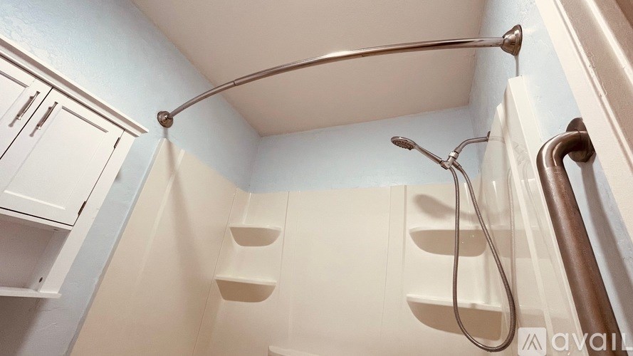 A shower with a metal rod and a white shower head.