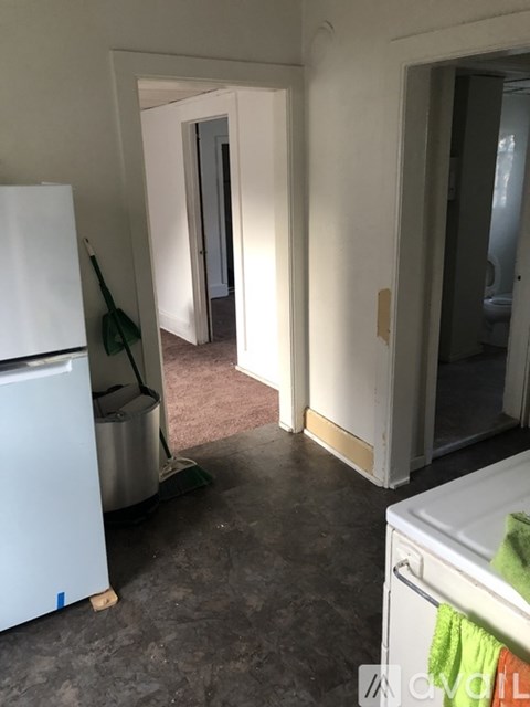 A white refrigerator is in a kitchen with a white door and a white wall.