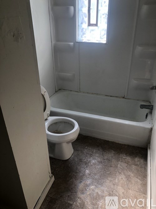 A white toilet in a small bathroom with a bathtub.