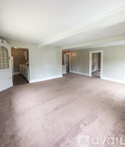 A large empty room with carpeted floor and white walls.