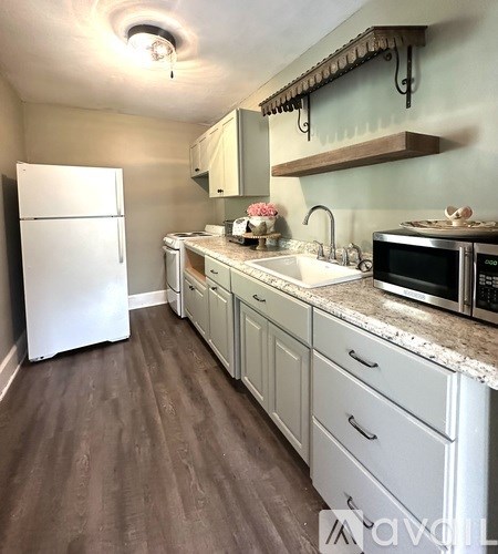 A kitchen with white appliances and wooden floors.