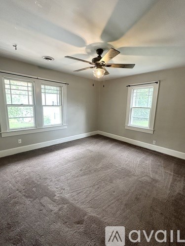 A room with a carpeted floor and a ceiling fan.