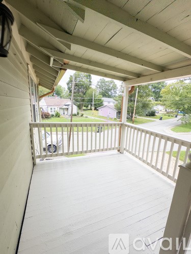 A white porch with a view of the street and houses.
