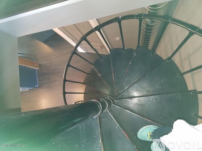 A spiral staircase with a black railing and steps.