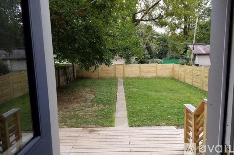 A backyard with a wooden deck and a fence.